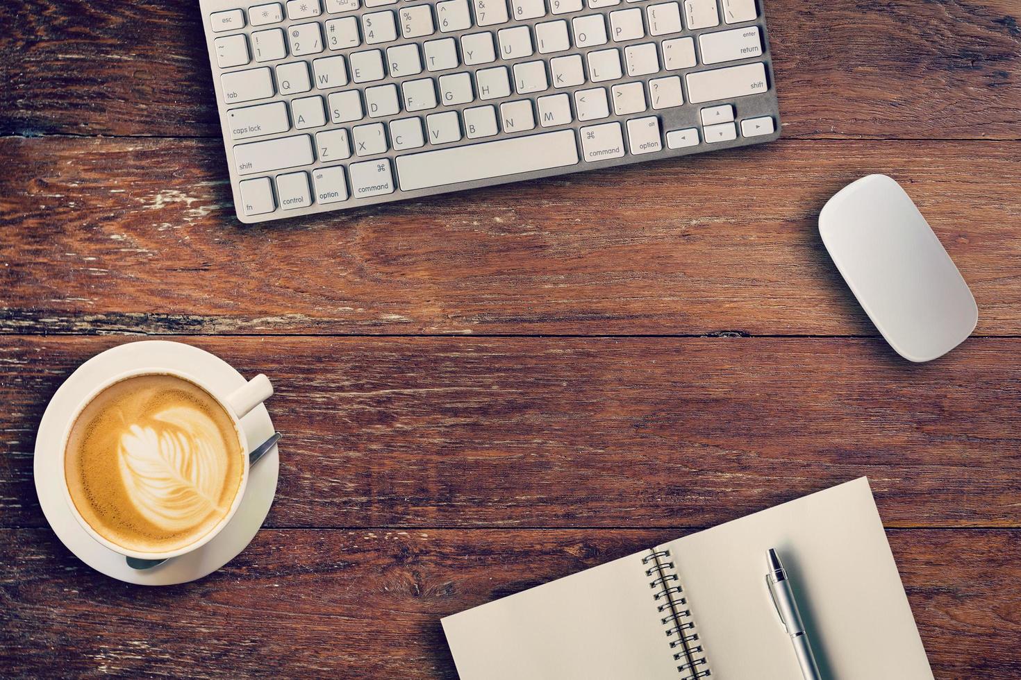 Office table with computer, notebook and coffee cup. View from above for vintage tone. photo