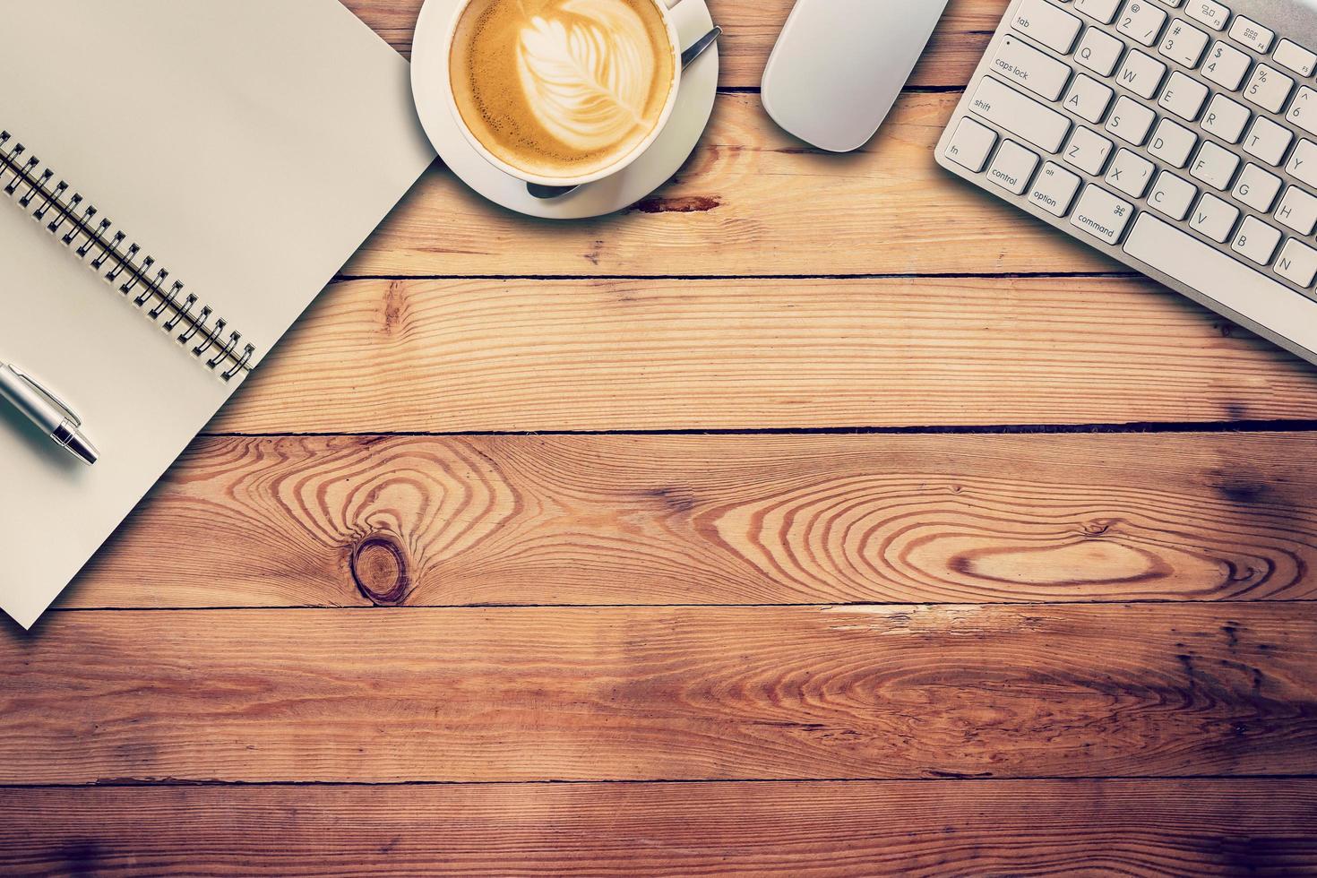 Office table with computer, notebook and coffee cup. View from above for vintage tone. photo