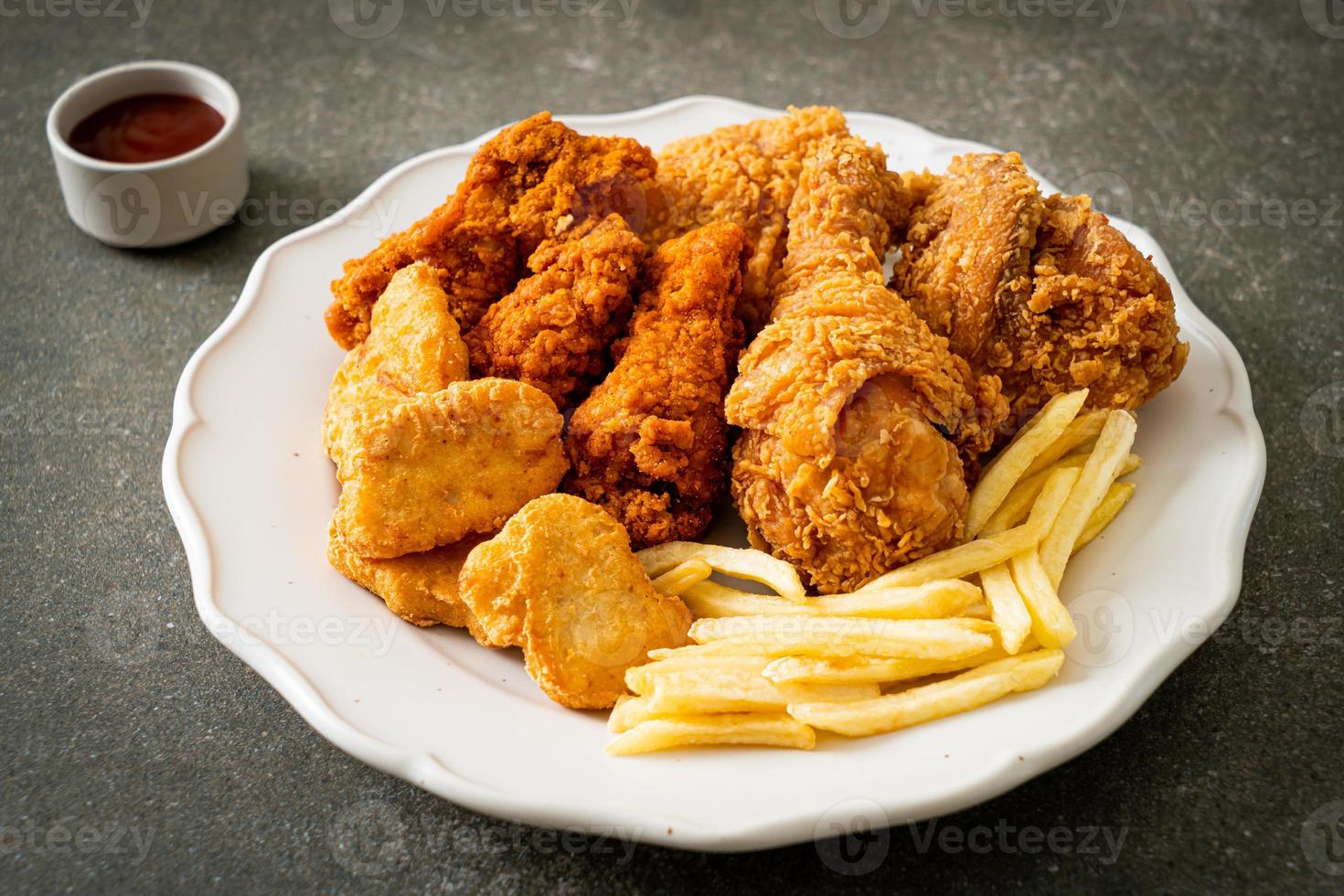 pollo frito con papas fritas y nuggets en un plato foto