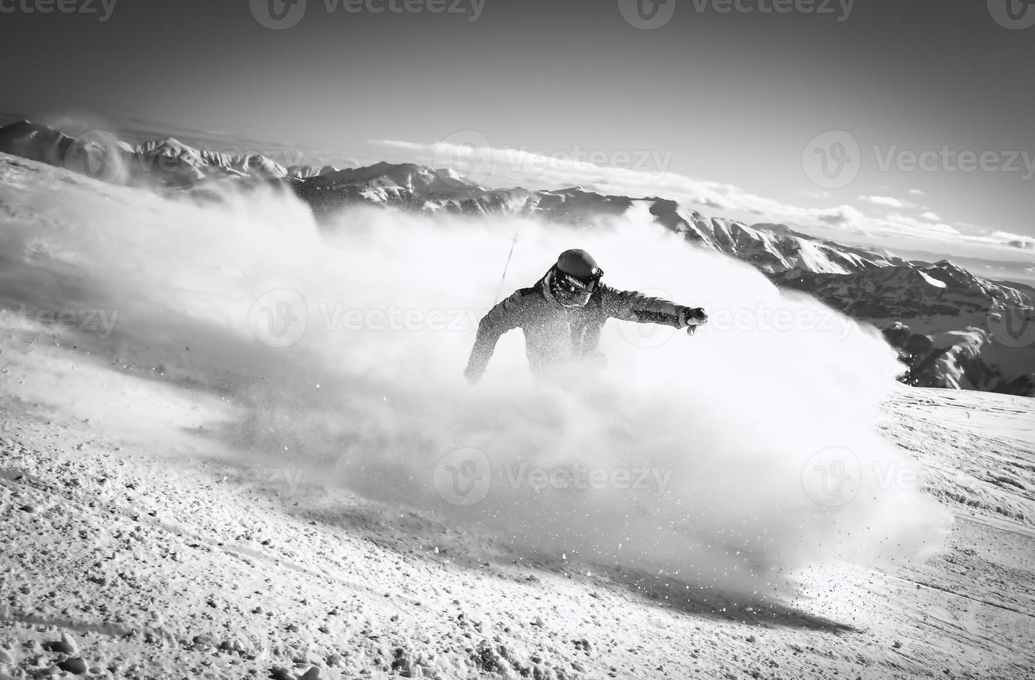 Professional skier at full speed ski downhill on fresh snow do carving in ski resort while training for competition in ski resort with mountains background photo