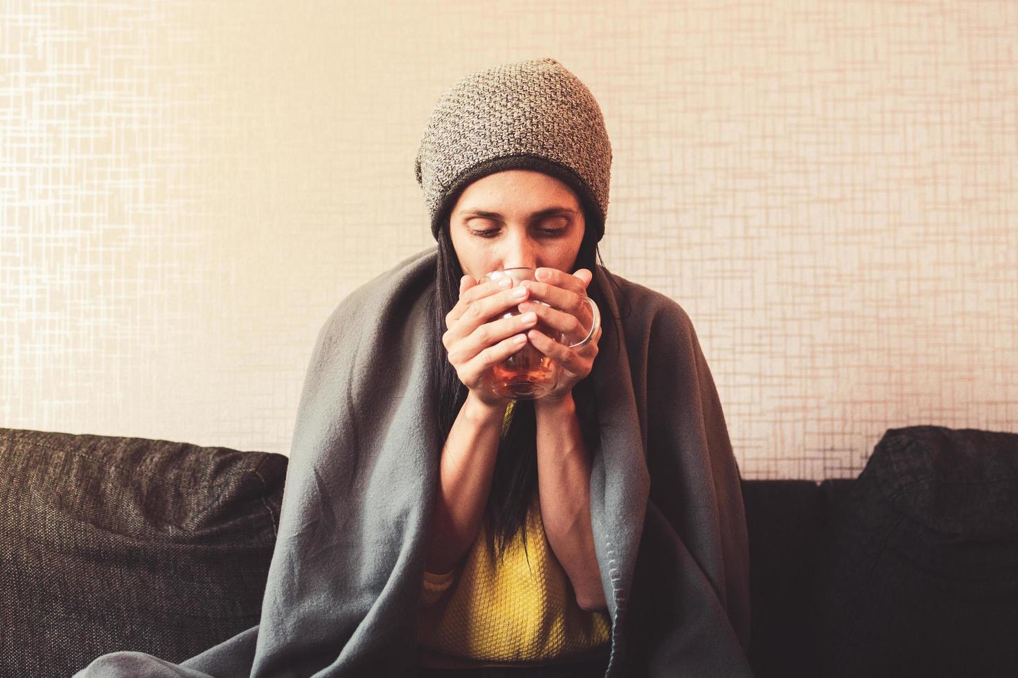 Caucasian Worried sad woman sits under blanket on sofa with cup of tea, Rising costs in private households for gas bill due to inflation and war, Energy crisis photo