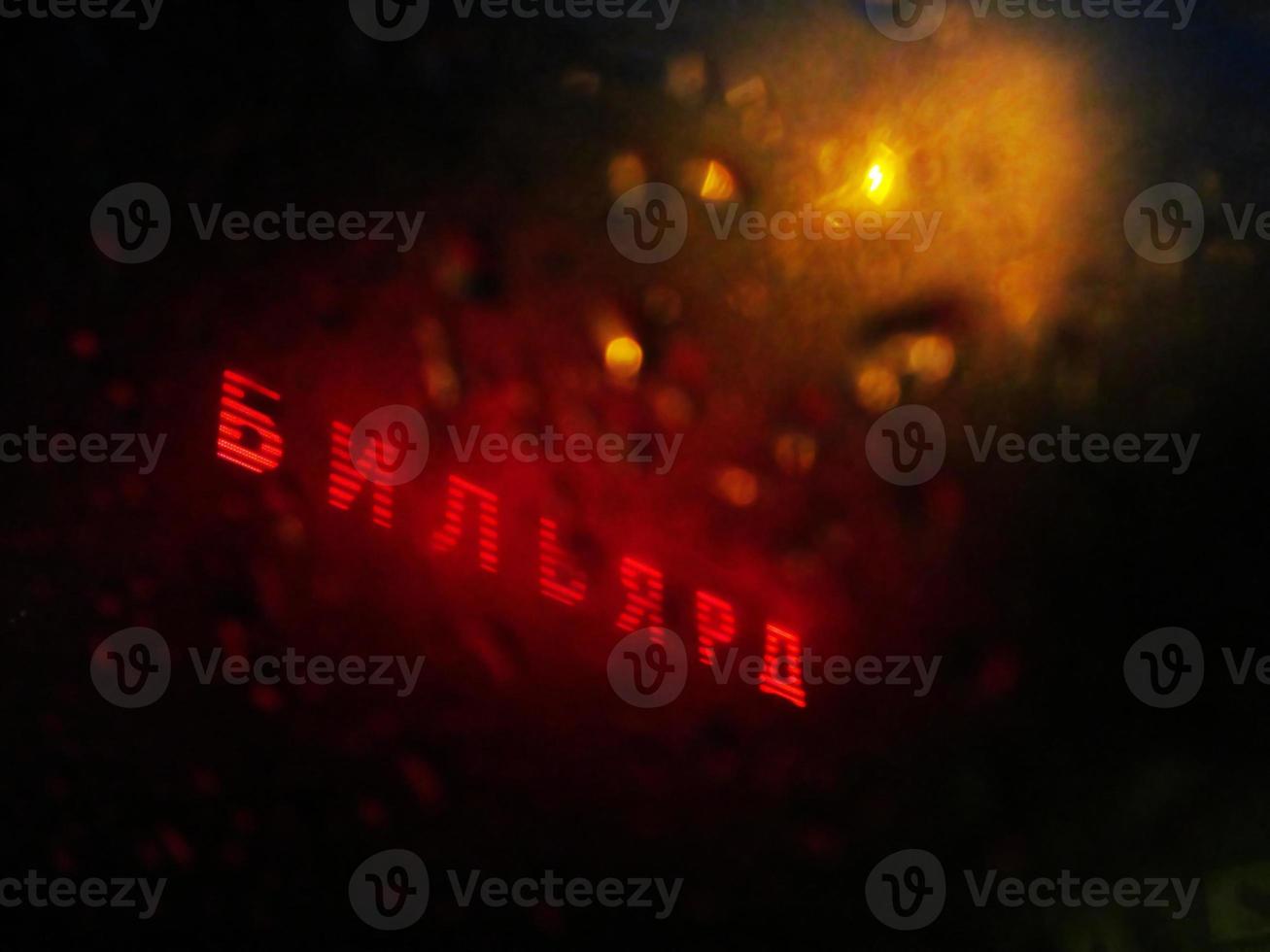 glowing signboard behind glass blurred by rain photo