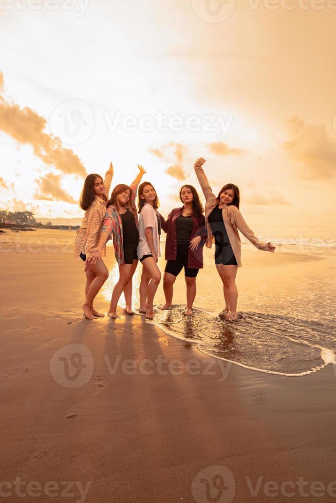 a group of Asian women in shirts posing happily while visiting a beautiful beach photo