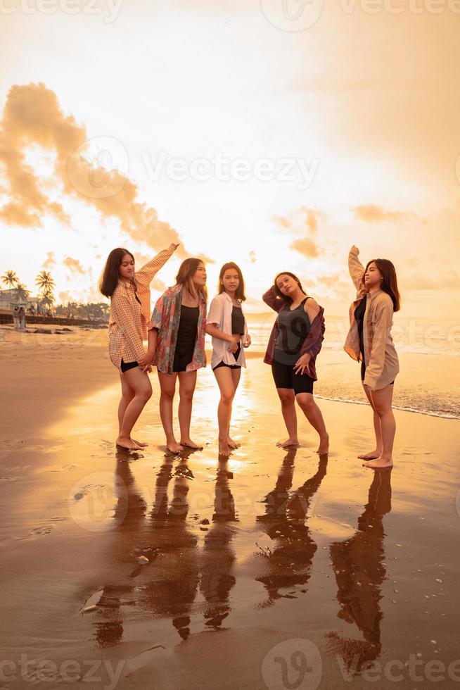 a group of Asian women in shirts posing happily while visiting a beautiful beach photo