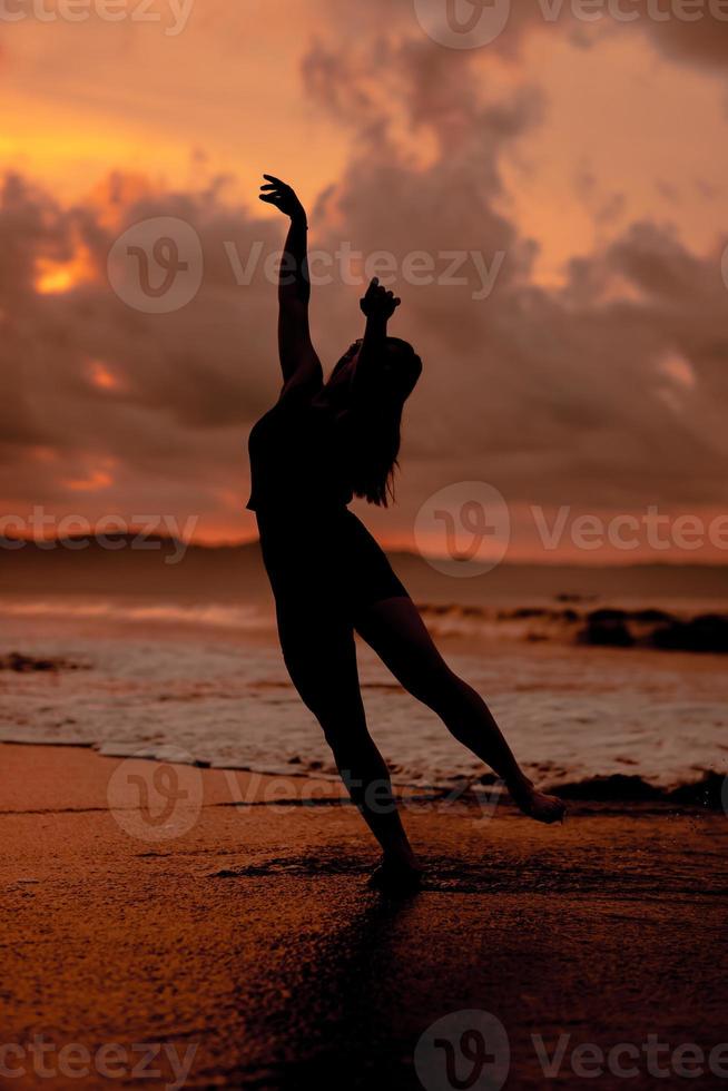 silhouette of an Asian woman playing in the water on the beach with strong waves crashing photo