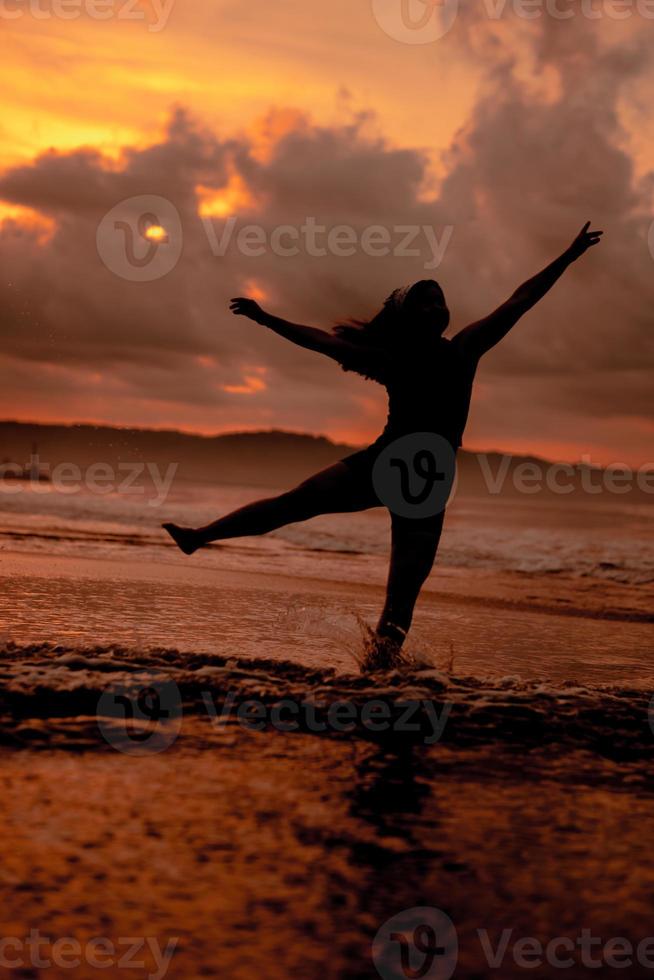 an Asian woman who is playing and dancing on the beach with strong waves photo