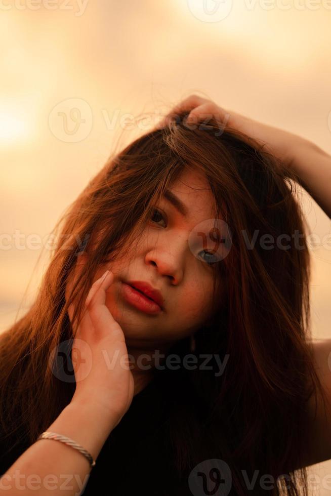 an Asian woman with blonde hair is posing by holding her head on the beach photo