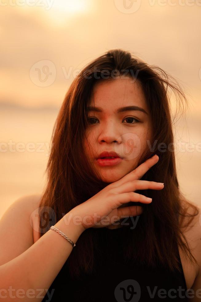 a beautiful and sexy Asian woman with flat facial expressions and posing with his hand under his chin photo