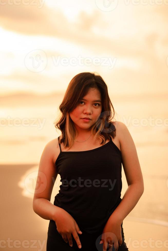 portrait of an Indonesian woman in black clothes and blonde hair posing very beautifully on the beach photo