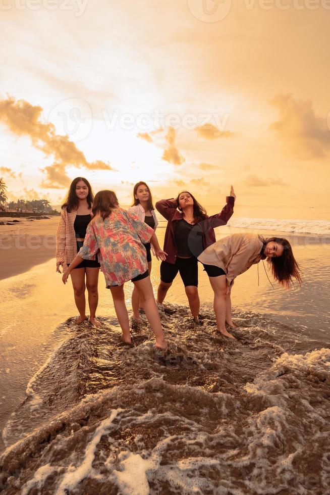 un grupo de indonesio mujer disfrutar el playa felizmente cuando ellos reunirse su amigos a el fiesta momento foto