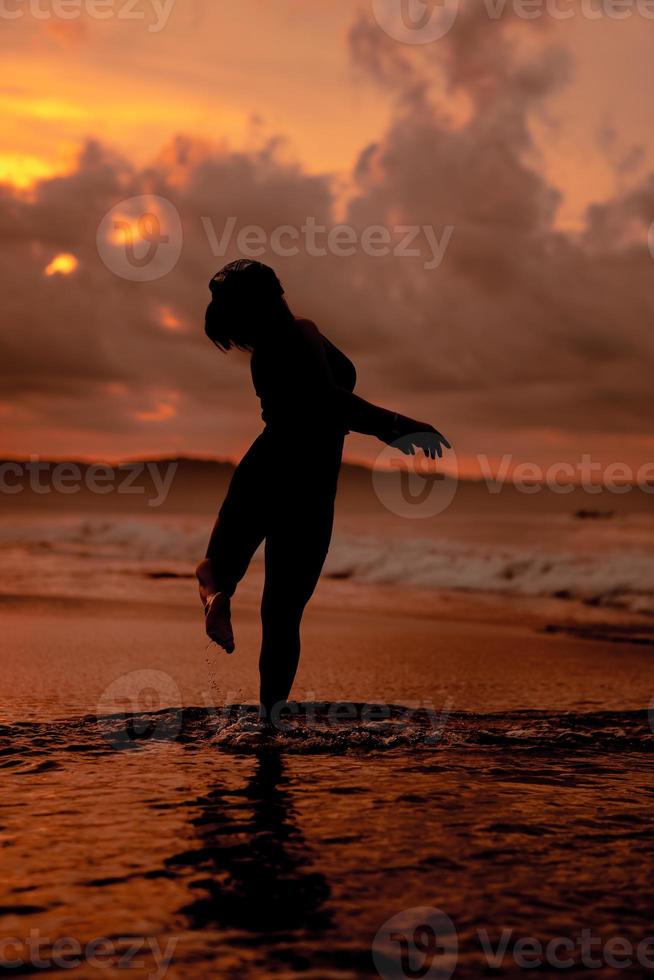 silhouette of an Asian woman playing in the water on the beach with strong waves crashing photo