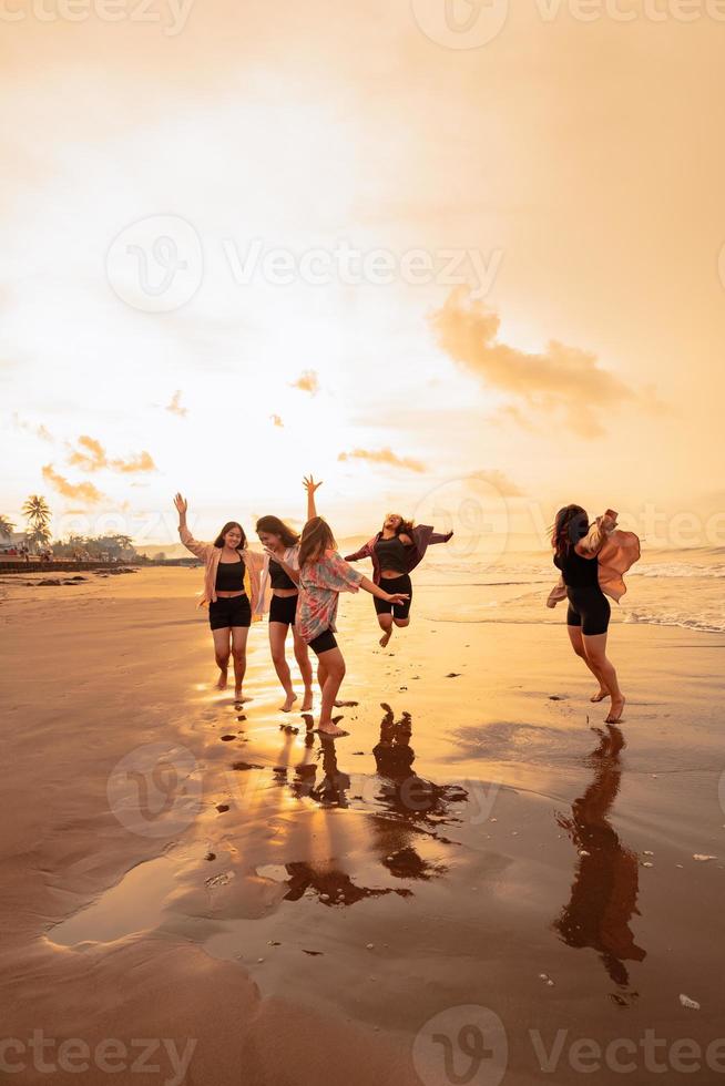 a group of Asian teenagers running with happy expressions on vacation with their friends drunk on the beach photo