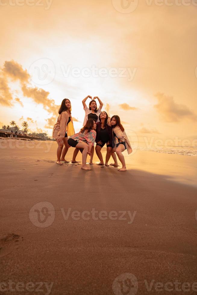 un grupo de indonesio mujer disfrutar el playa felizmente cuando ellos reunirse su amigos a el fiesta momento foto