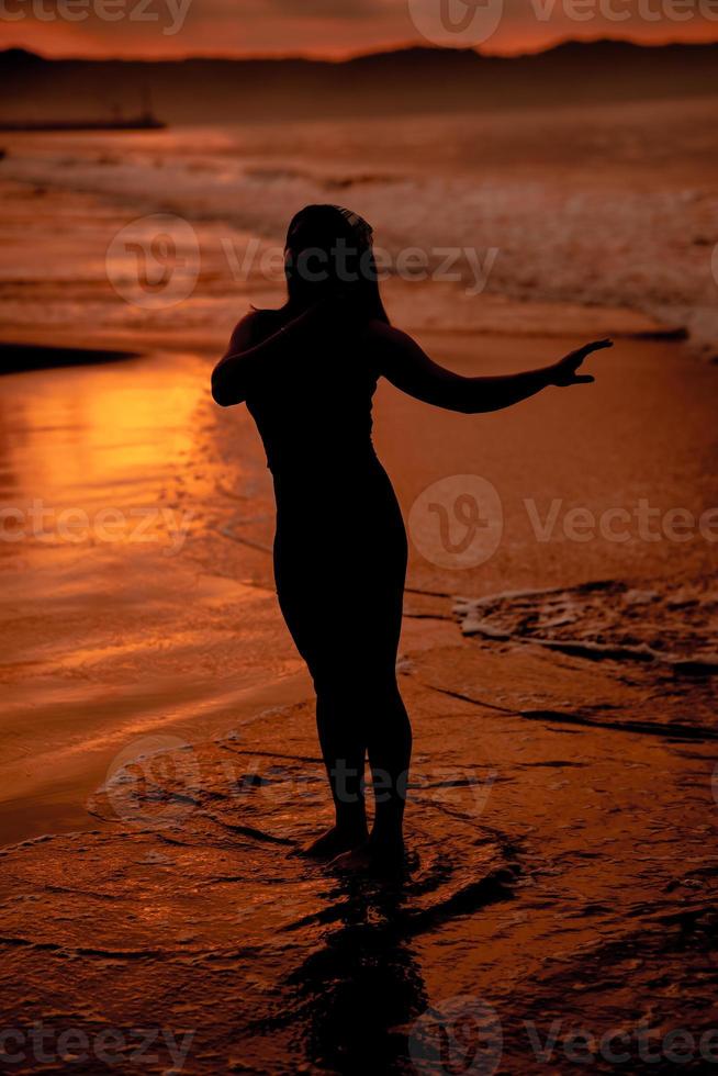 silhouette of an Asian woman playing in the water on the beach with strong waves crashing photo