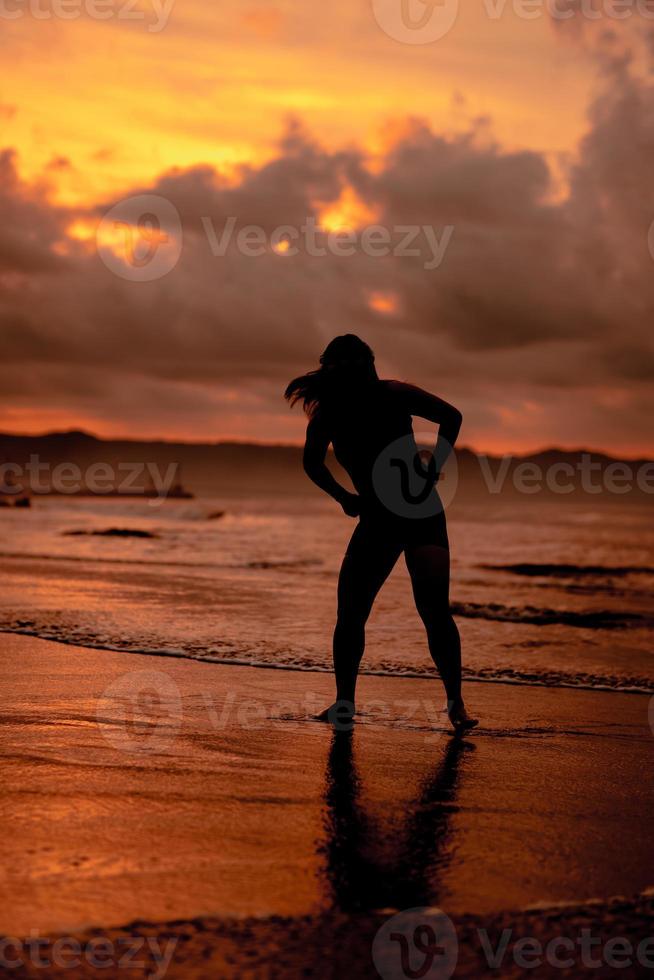 an Asian woman who is playing and dancing on the beach with strong waves photo