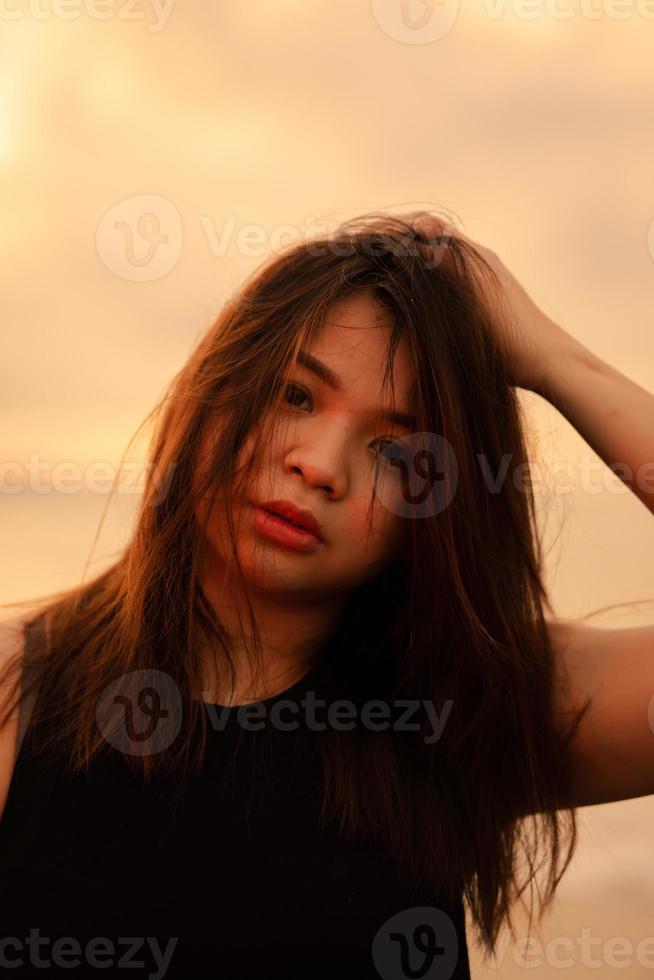 a beautiful and sexy Asian woman with a facial expression that looks messed up while standing on the beach photo