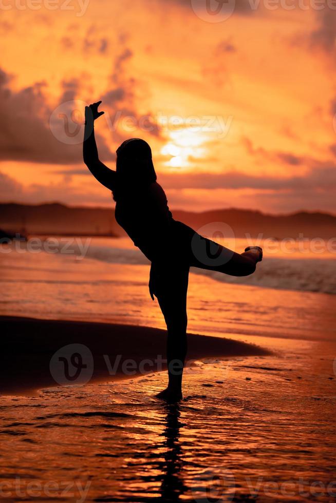 an Asian teenager dancing ballet in black for a festival by the beach photo