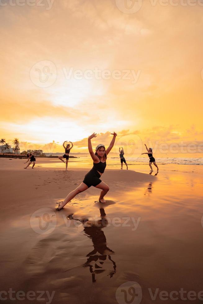 a group of Indonesian women doing ballet movement exercises together very flexibly on the beach photo