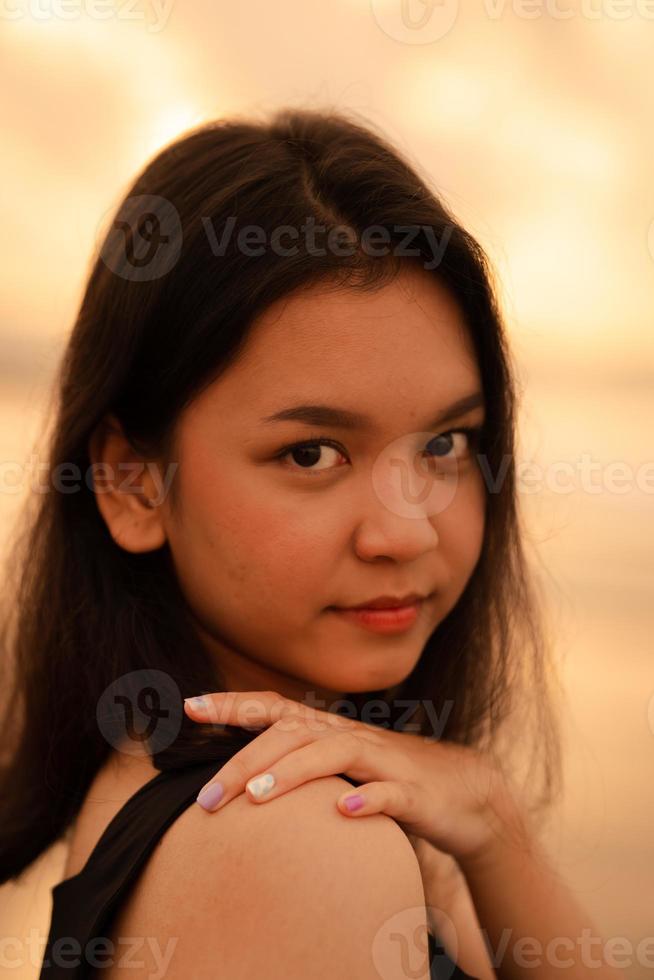 un asiático Adolescente mujer con un negro camisa y negro pelo tiene un linda cara cuando ella sonrisas y disfruta el ver foto