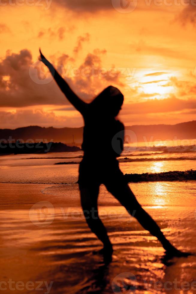 el silueta de un asiático adolescente con un alto cuerpo es bailando ballet en el olas en el playa foto