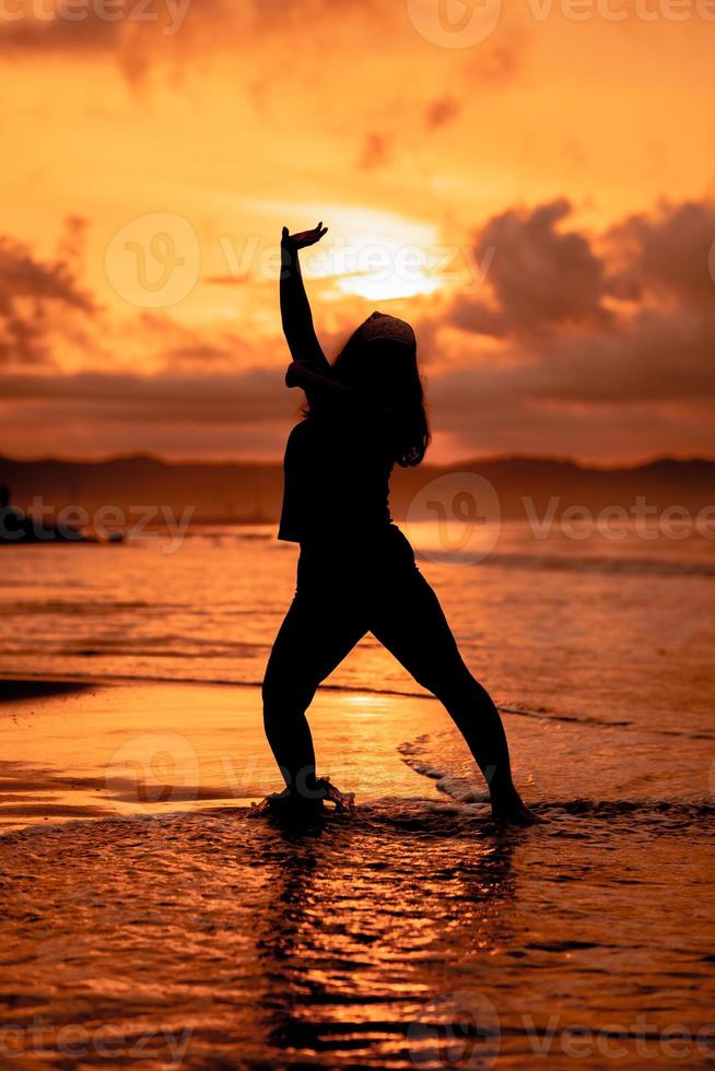 silhouette image of an Asian woman doing ballet movements very flexibly on the beach photo