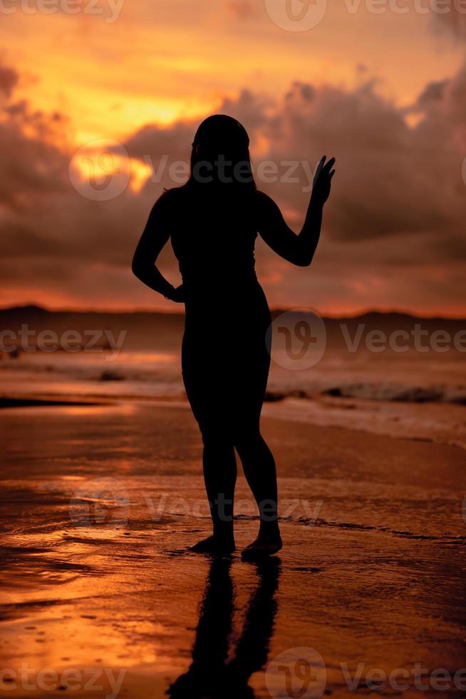 silueta de un asiático mujer jugando en el agua en el playa con fuerte olas estrellarse foto