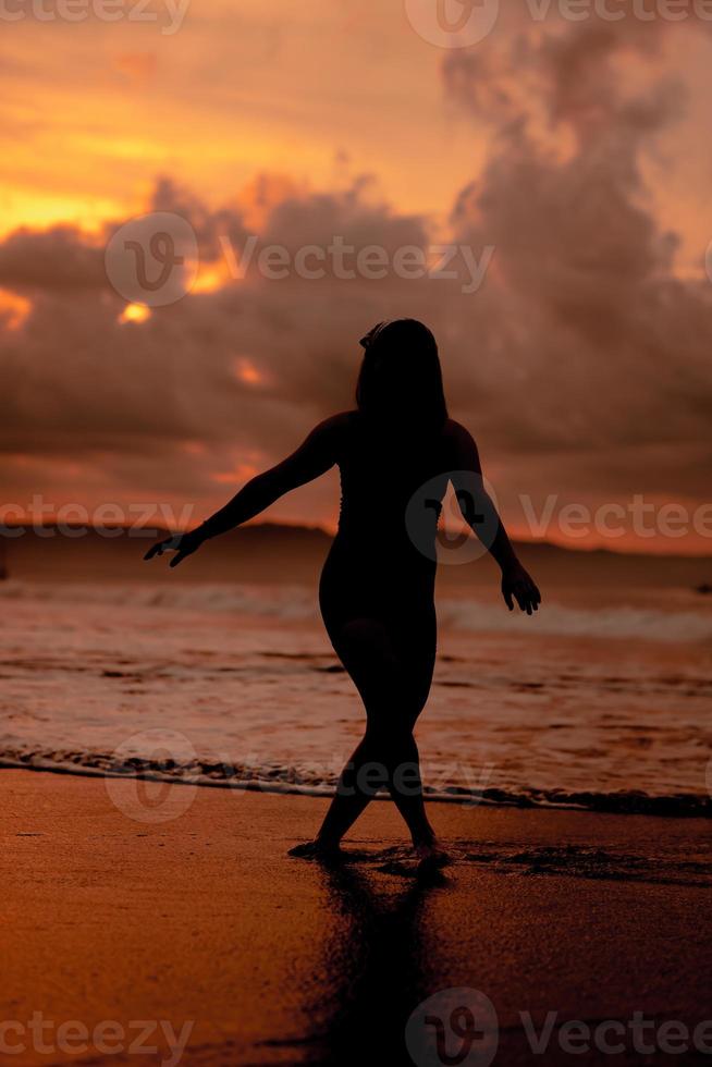 silhouette of an Asian woman playing in the water on the beach with strong waves crashing photo