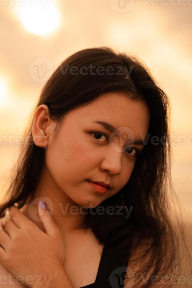 un asiático Adolescente mujer con un negro camisa y negro pelo tiene un linda cara cuando ella sonrisas y disfruta el ver foto