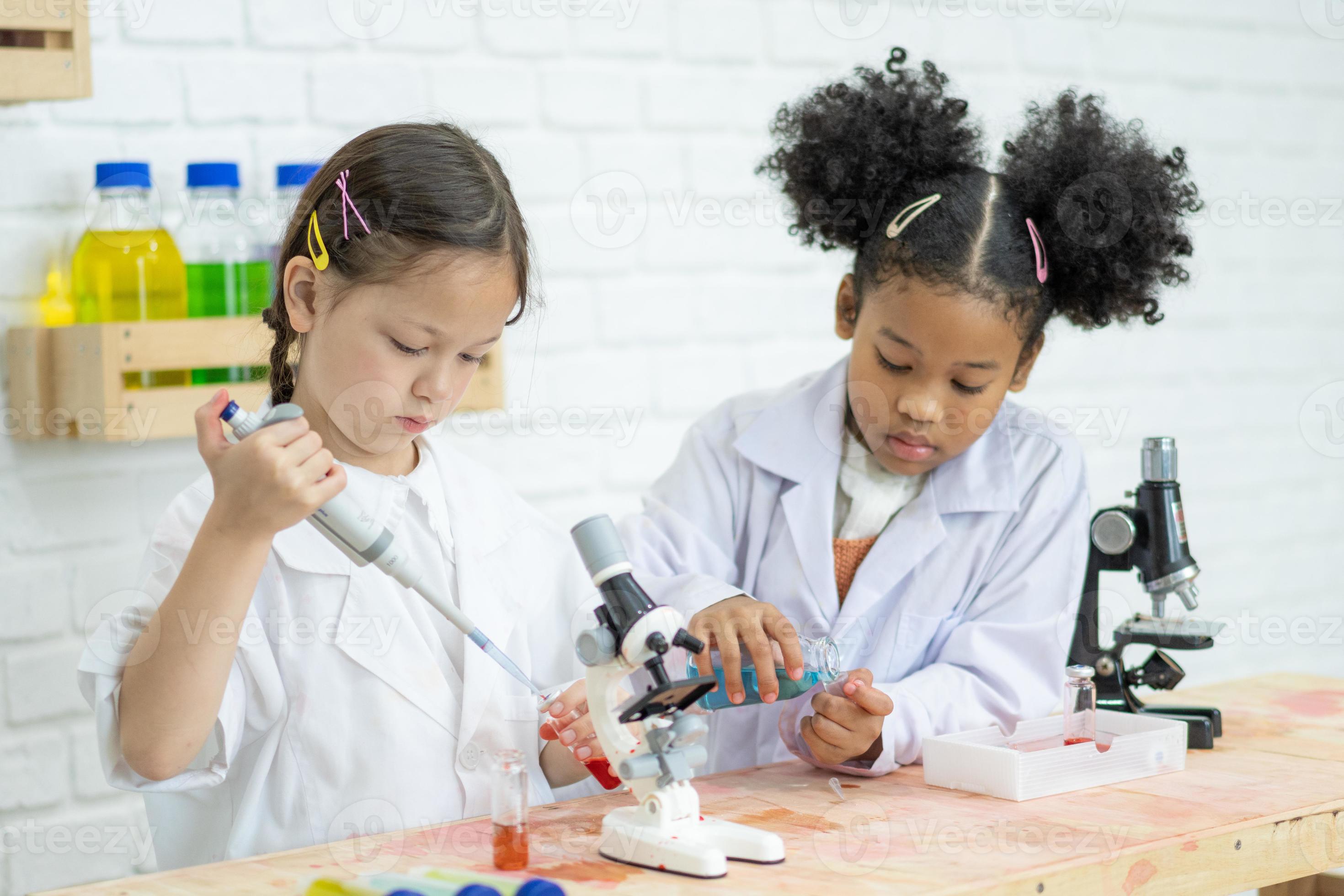 Two little kids in lab coat learning chemistry in school laboratory
