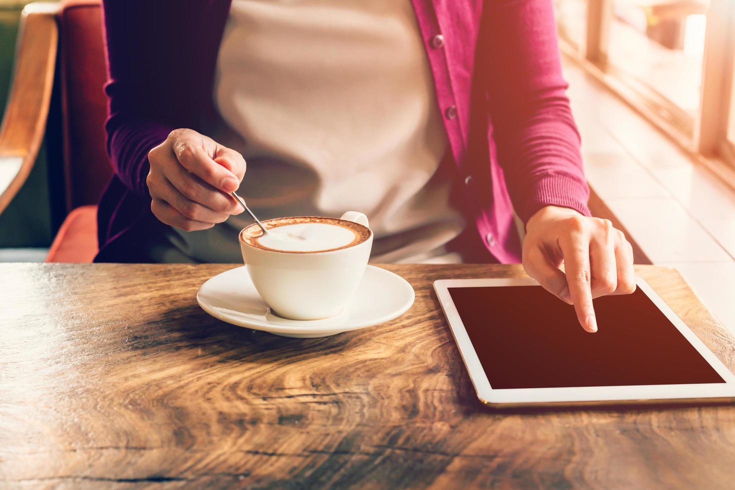 hand woman touchscreen tablet computer and cup in coffee shop with vintage tone. photo