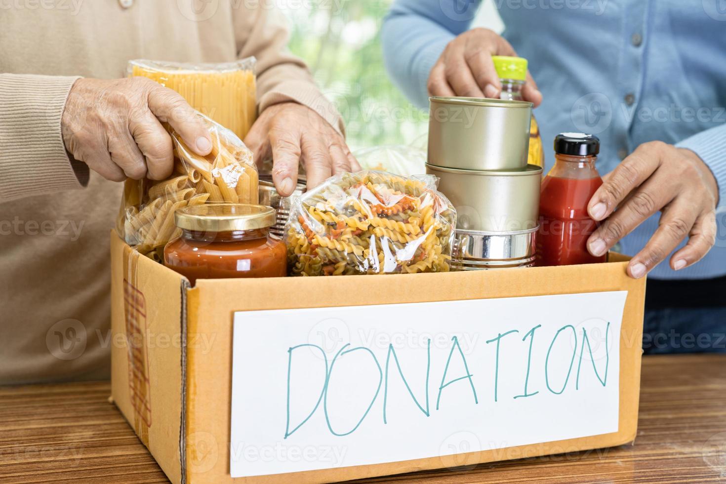 Volunteers putting various dry food in donation box for help people. photo