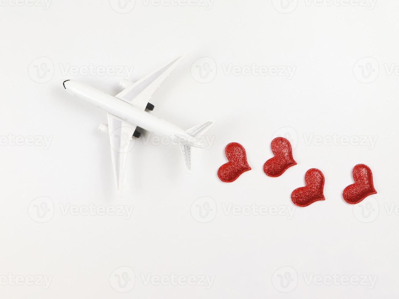 flat lay of airplane model with red hearts on white background. Honeymoon trip or travel lover concept. photo