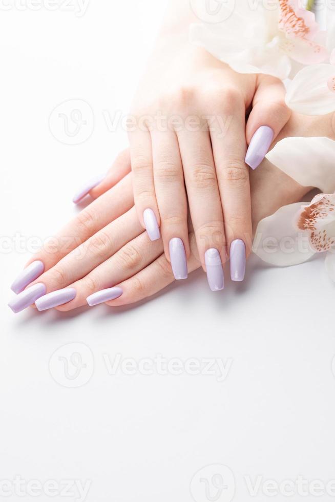 Girl's hands with delicate purple manicure and orchid flowers photo
