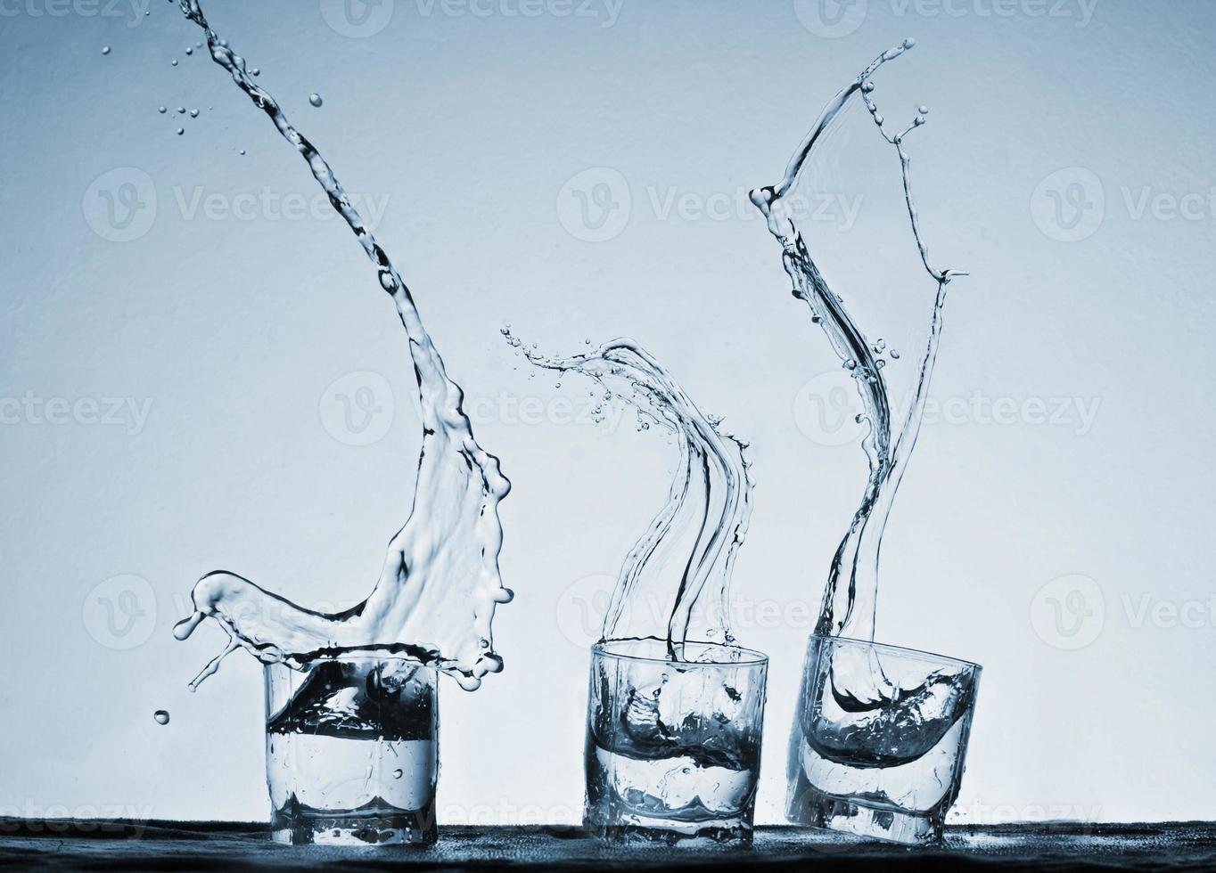 Big splash in three glasses on a blue background photo