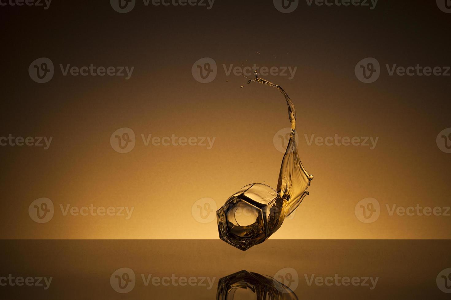 Falling glass of alcoholic drink on a golden background photo