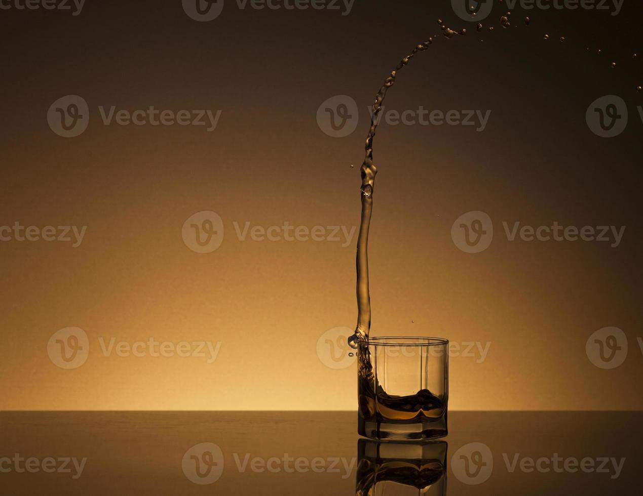 Glass of alcoholic drink on a golden background photo