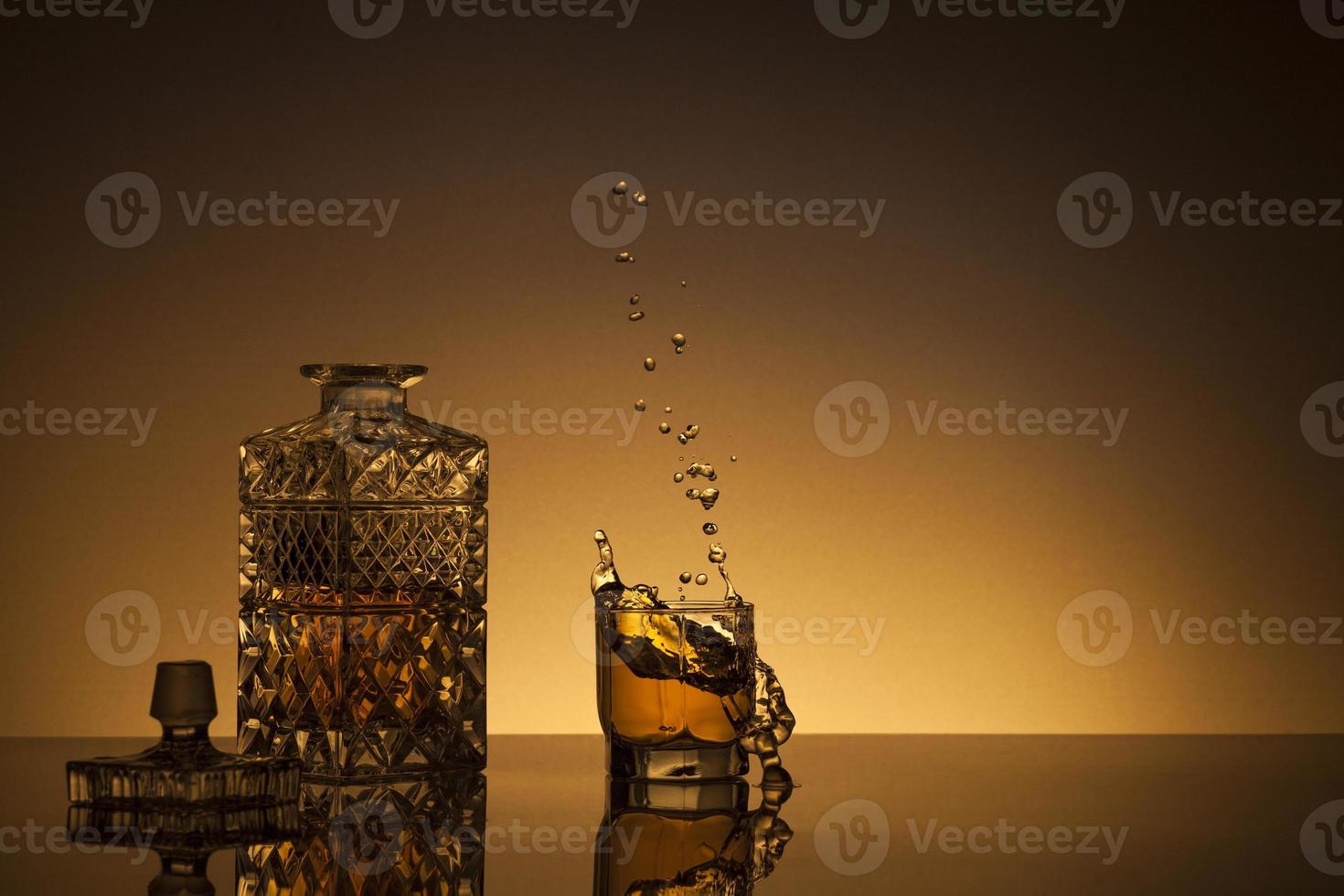 Decanter and glass with whiskey on golden background photo