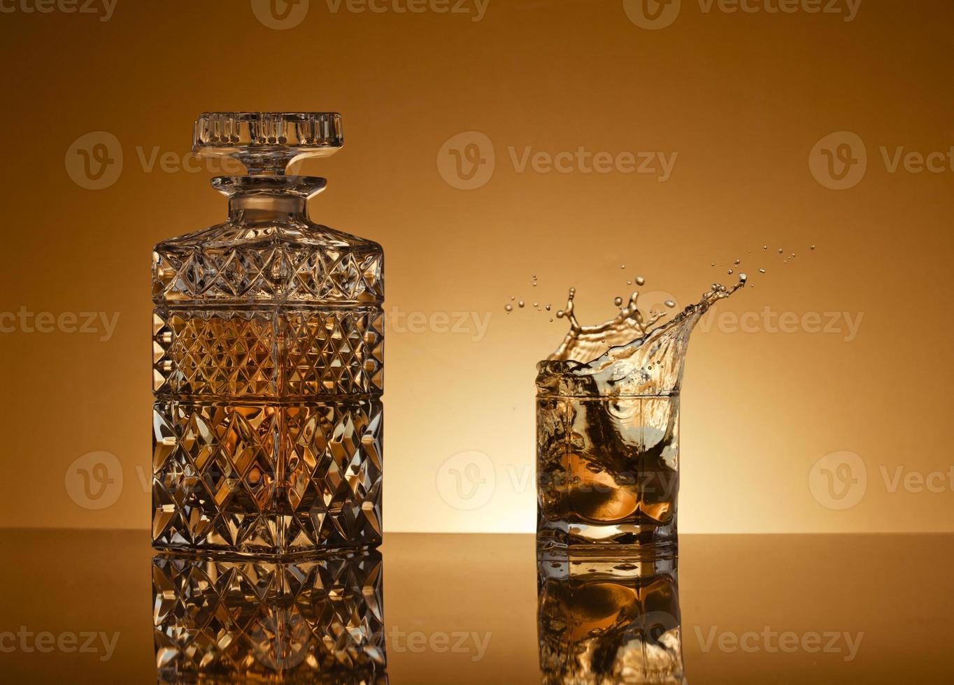 Decanter and glass with whiskey on golden background photo