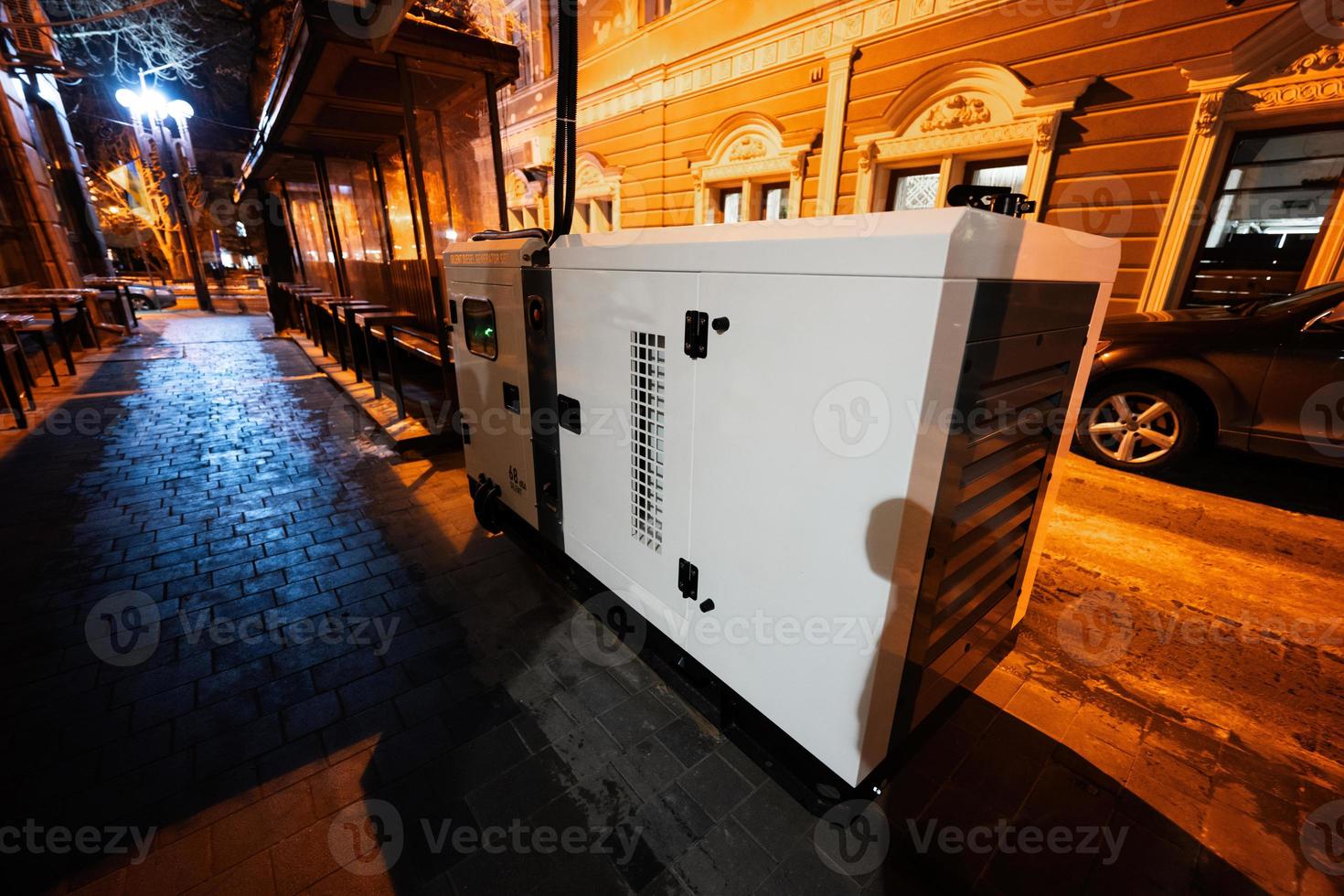 Large stationary diesel power three phase electric silent generator set in evening city. photo