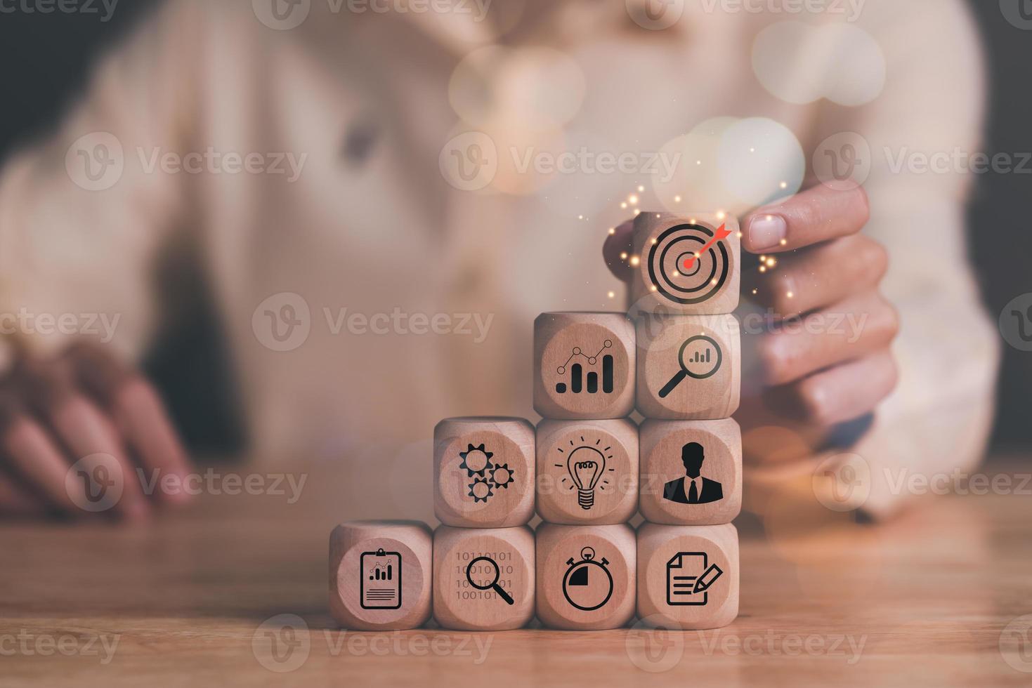 Man holding wooden block on table, businessman and arrow icons hitting center of dart board target, set business goals and focused concept, corporate growth and objectives,marketing strategy planning photo