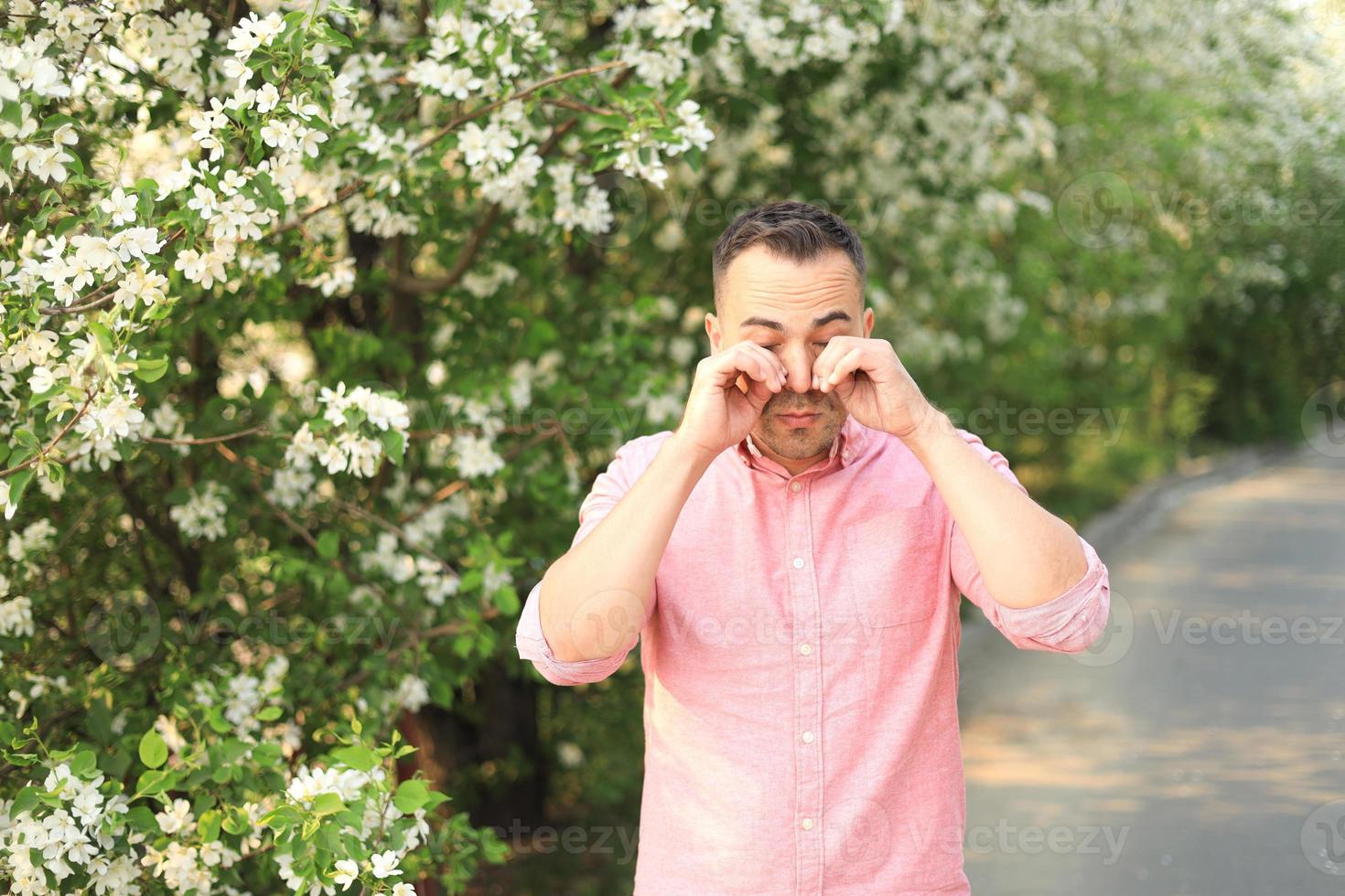 Upset man crying while wiping his watery eyes photo