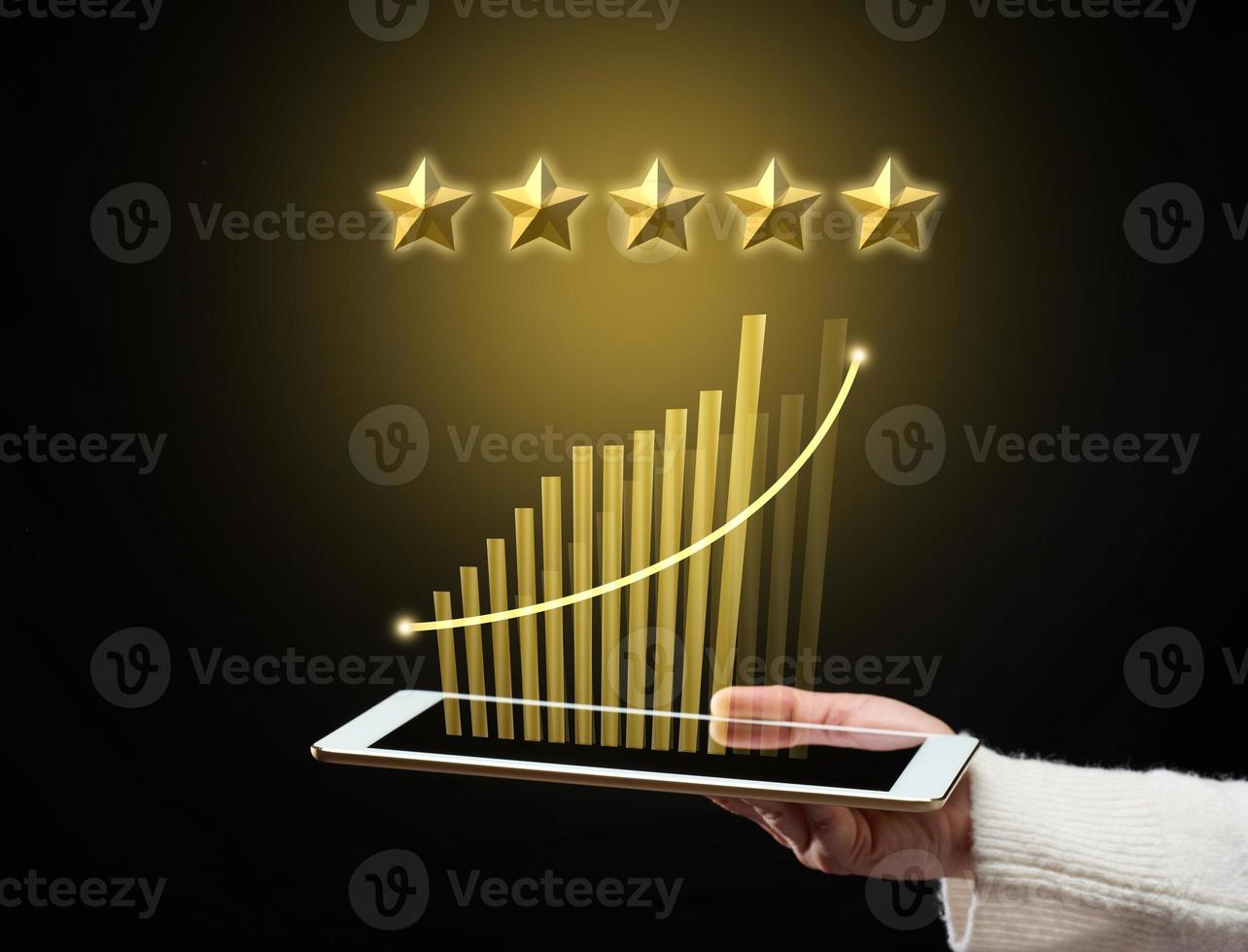 female hand holds a tablet and five gold stars above it. App evaluation. User reviews, business rating photo