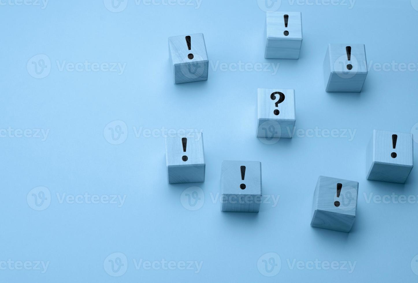 wooden cubes with exclamation marks and a question mark in the middle on a light blue background photo