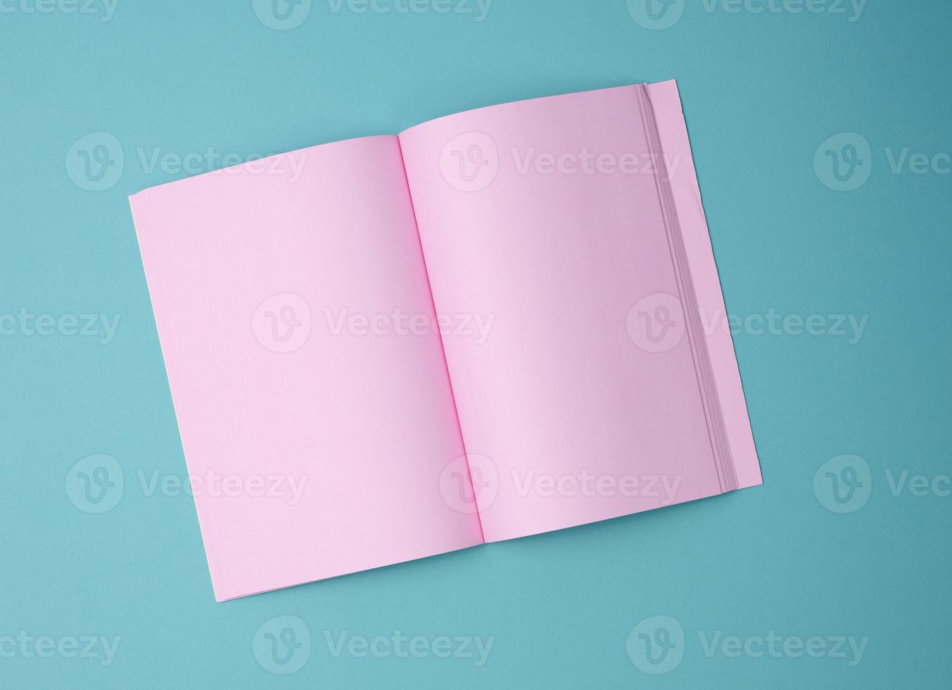 open notebook with blank pink sheets on blue background, top view photo