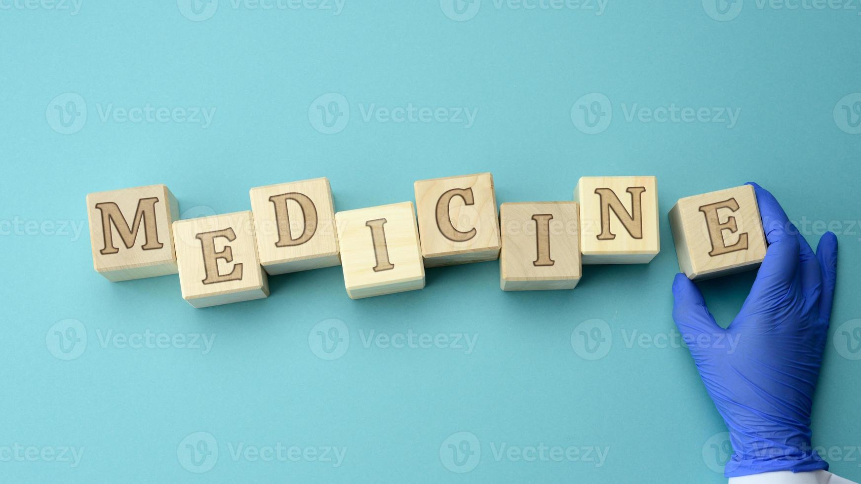 wooden cubes with the inscription medicine and the hand of a doctor in a blue latex glove, health insurance concept photo