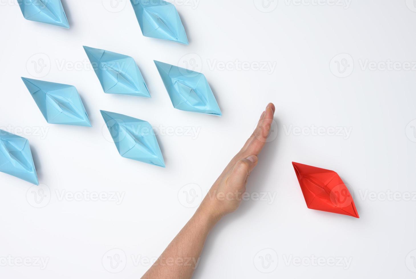 female hand between paper boats on a white background, concept of reconciliation of the parties, the search for compromise photo