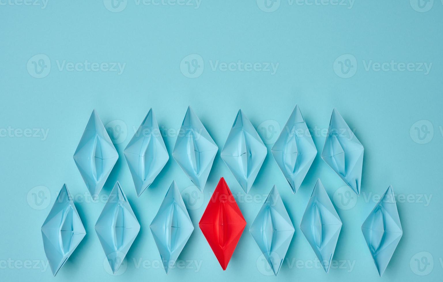 group of paper boats on a blue background. concept of a strong leader in a team, manipulation of the masses, following new perspectives, collaboration and unification. Startup photo