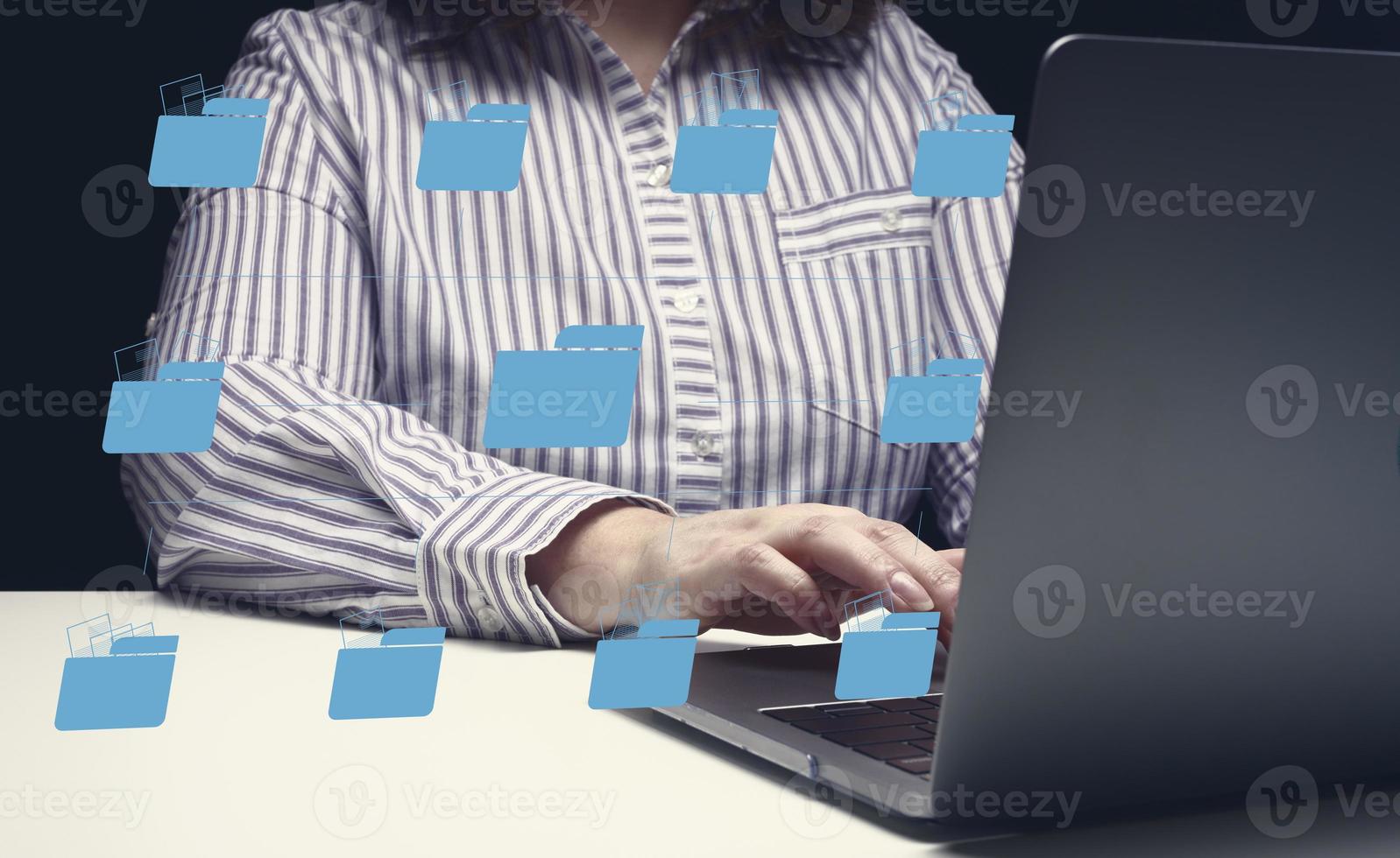 Woman sits at a table and works with a laptop. Document management system DMS photo