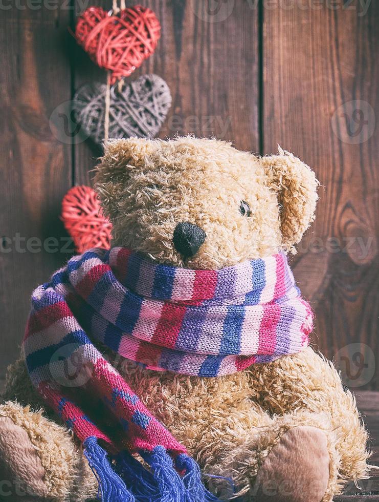 brown soft teddy bear sit on a brown wooden background photo