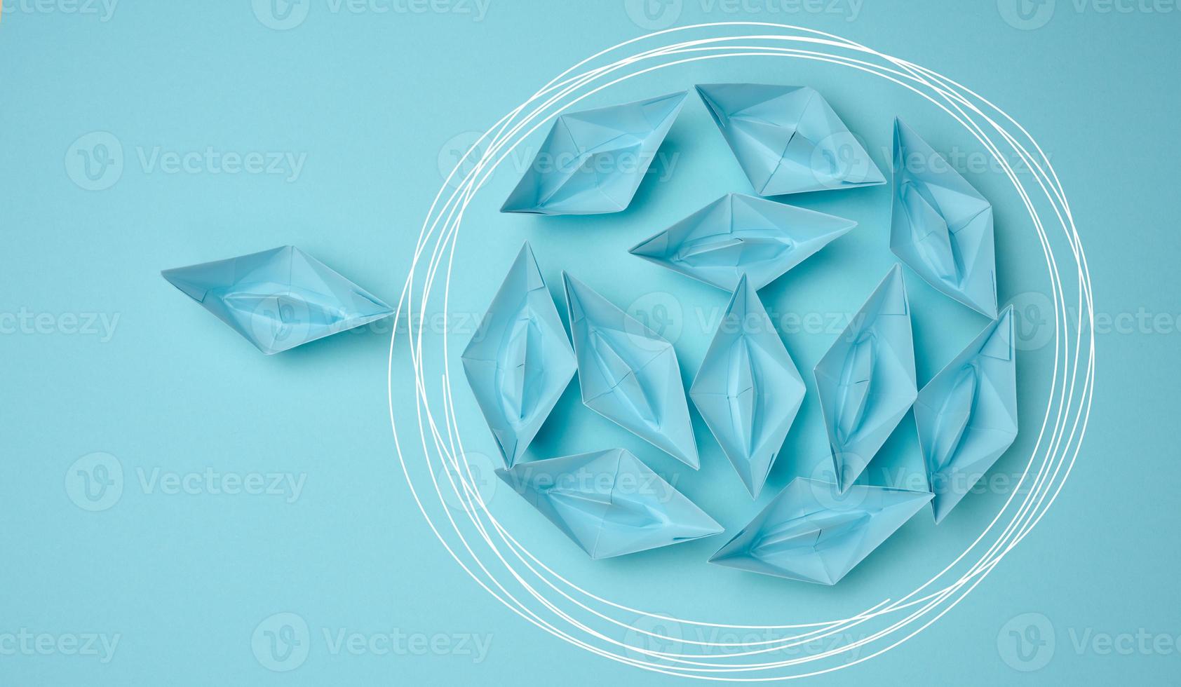 group of paper boats floats in a circle, another red floats in a straight line. Strong leader concept, different vision, strong business. Looping over an idea photo